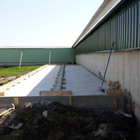 Concrete foundation poured along an existing barn wall with anchor bolts set for a filter wall dormer